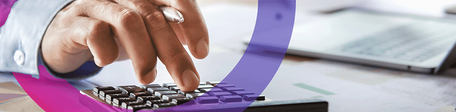 Hand typing on calculator doing finances. pink and purple cora lens on left of picture