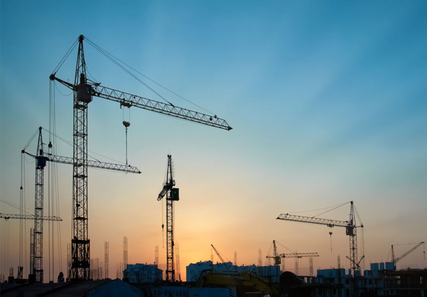 A view of numerous cranes with a sunset back drop