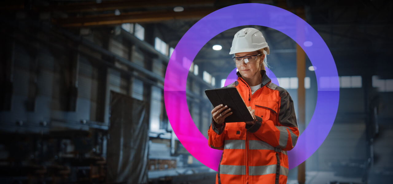Civil engineer lady wearing a white hard hat and an orange high vis looking at project updates on her ipad standing in a factory. cora lens circling the lady.