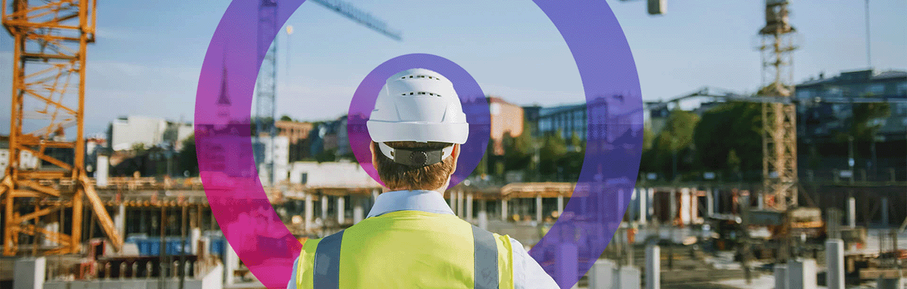 Civil Engineer wearing a high visibility jacket and hard helmet standing at site looking at building.