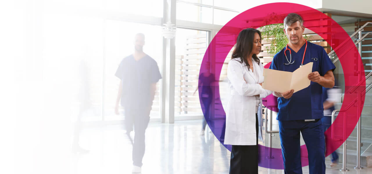 One male doctor wearing blue scrubs and one female doctor in a white lab coat reviewing project data with a pink cora lens circling them.