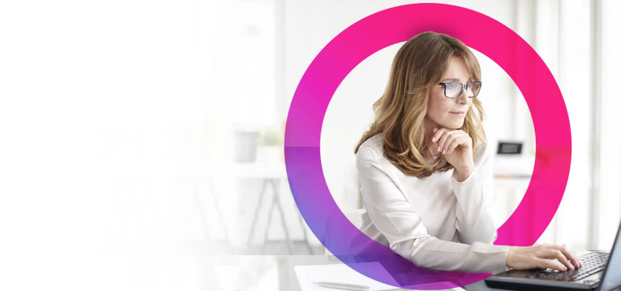 A lady with blonde hair wearing glasses working on her laptop with a pink and blue cora lens circling her