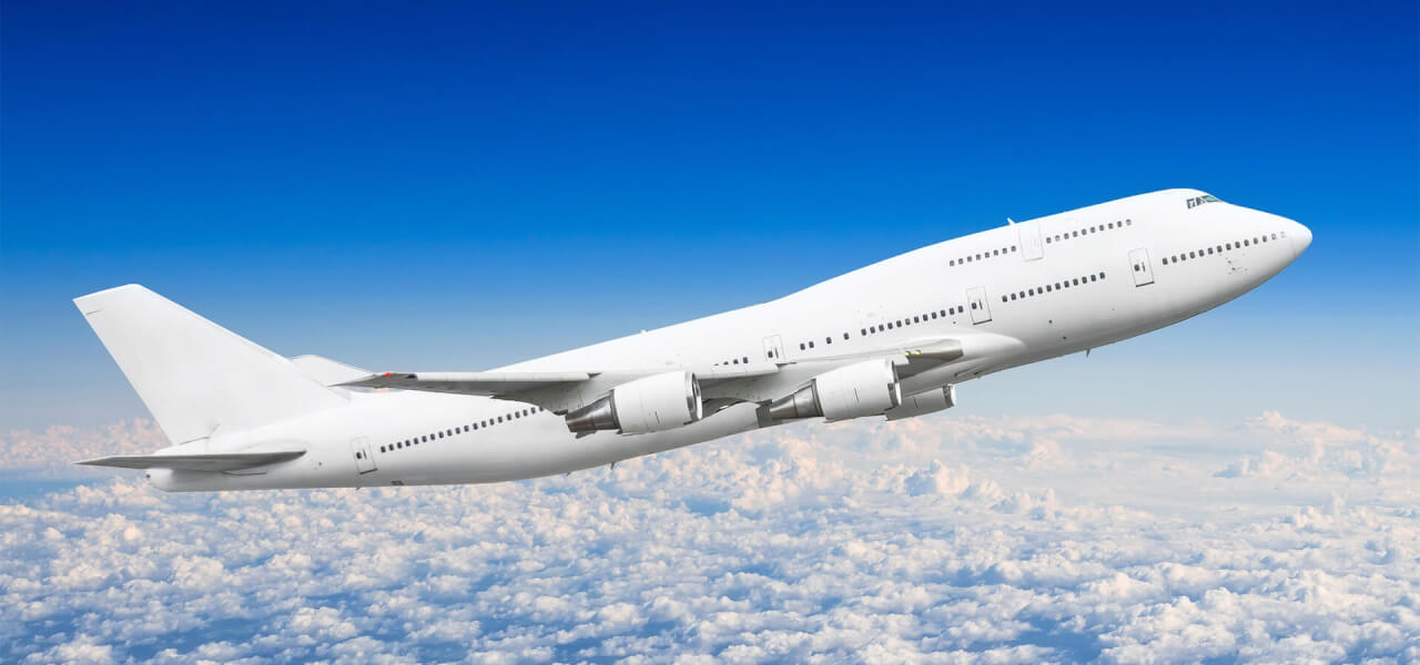 aircraft in mid flight in the sky with white clouds and a light blue sky in the background