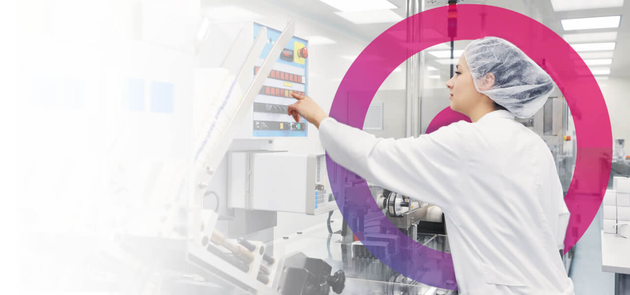 Science lab woman wearing a hair net and white lap coat turning on a machine. pink Cora lens in back right of photo.