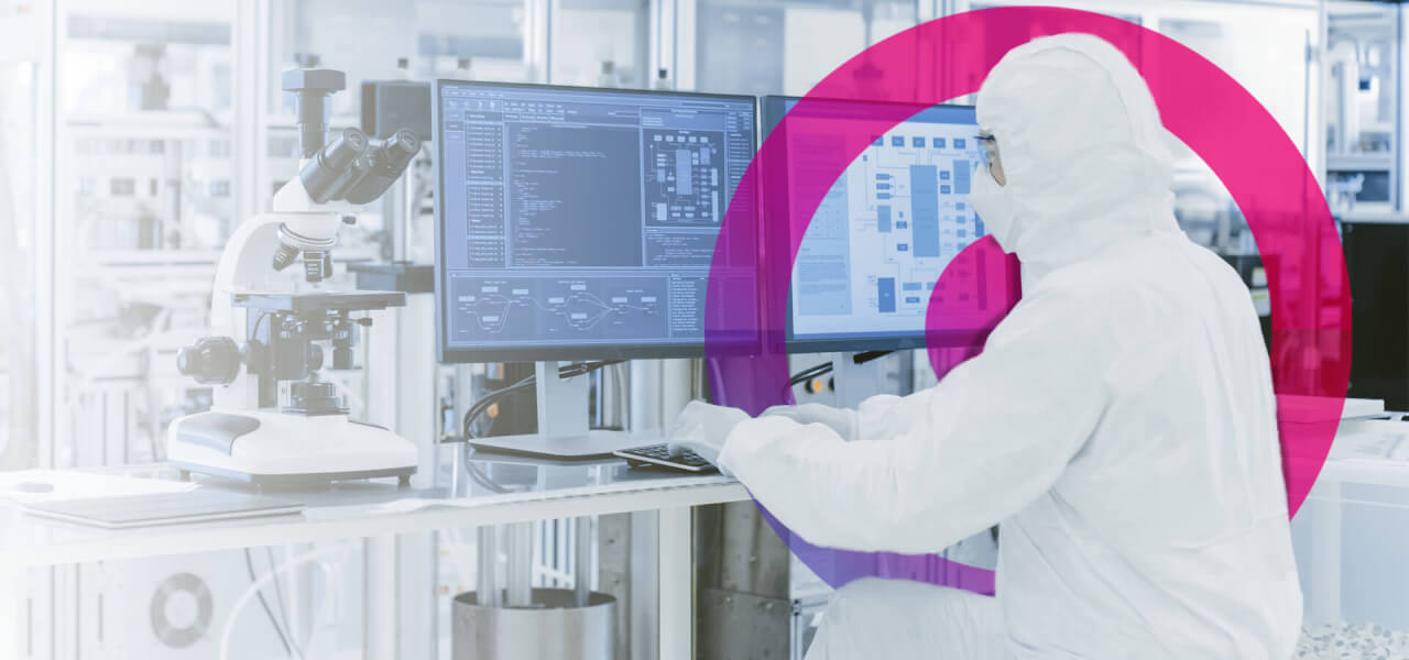 Scientist wearing a white all in one lab suit working a computer analysing data.