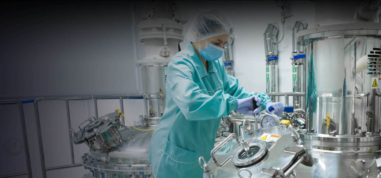 Lady wearing a blue all in one lab coat and hair net working in a factory