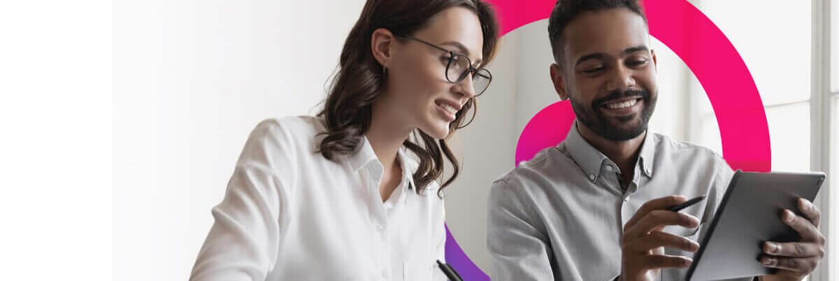 Man and woman talking in an office smiling looking at an iPad.