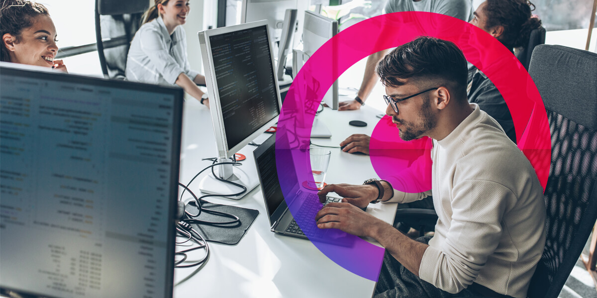 Man with light brown hair and glasses working at his laptop in the office wearing a white shirt. Pink and purple lens graphic in the background.