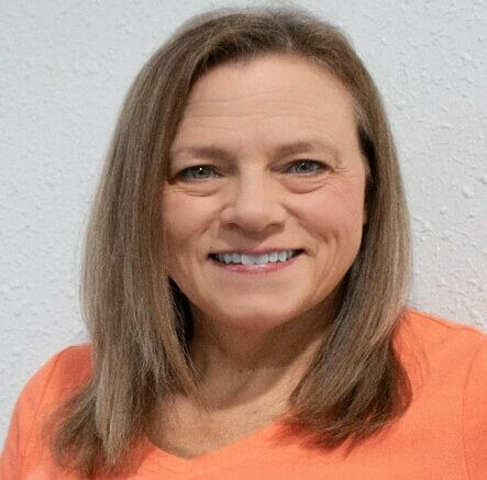 Image of woman smiling wearing an orange jumper