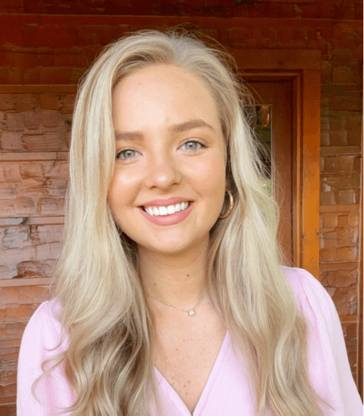 Blonde woman wearing a pink blouse. 